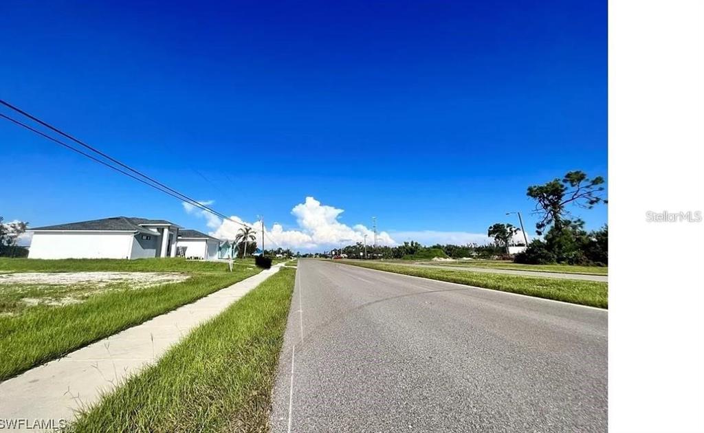A paved road stretches into the distance past a sidewalk and a single-story house — 2703 CEITUS PARKWAY, CAPE CORAL, FL