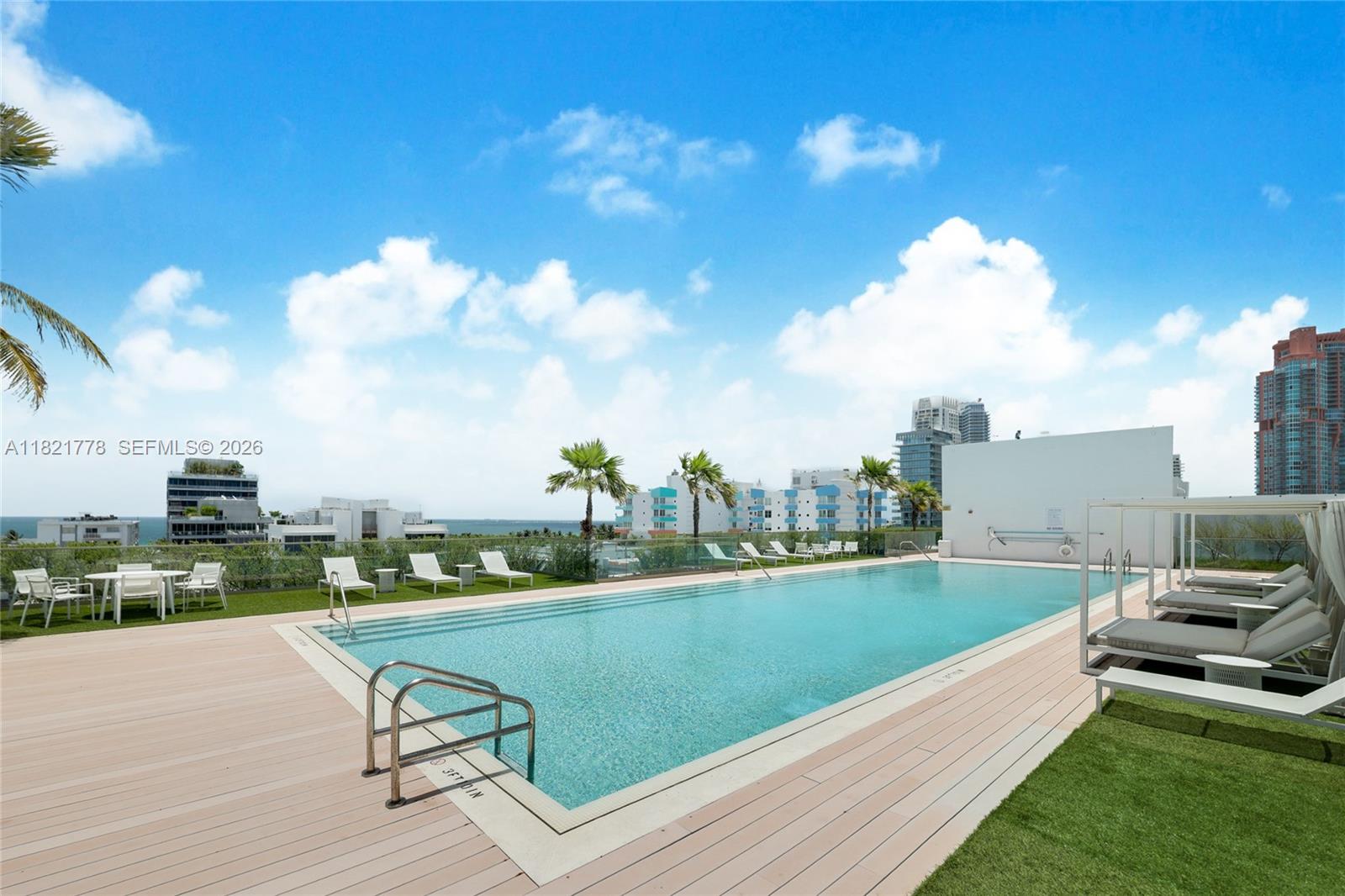 An outdoor swimming pool on a wooden deck features lounge chairs and city skyline views — 300 Collins Ave # 3D, Miami Beach FL 33139, MIAMI BEACH, FL