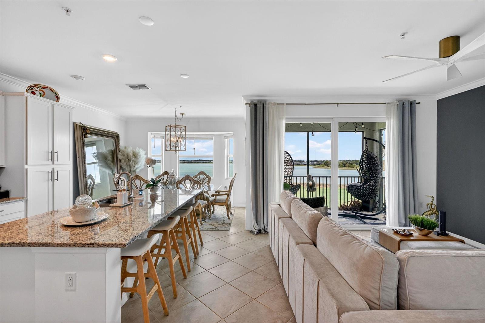 An open-concept kitchen and living area features a granite island, tile floors, and balcony views — 43050 Greenway Boulevard # 645, Punta Gorda FL 33982, PUNTA GORDA, FL