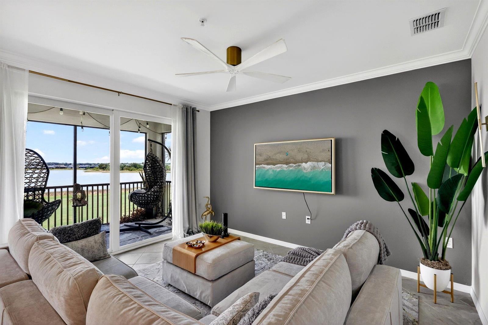 A living room features a grey accent wall, a wall-mounted television, and a balcony view — 43050 Greenway Boulevard # 645, Punta Gorda FL 33982, PUNTA GORDA, FL