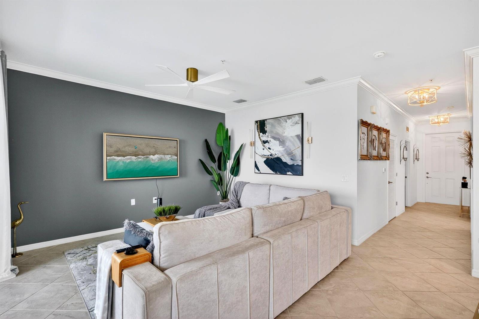 A living room features a gray accent wall, a beige sectional sofa, and tile flooring — 43050 Greenway Boulevard # 645, Punta Gorda FL 33982, PUNTA GORDA, FL