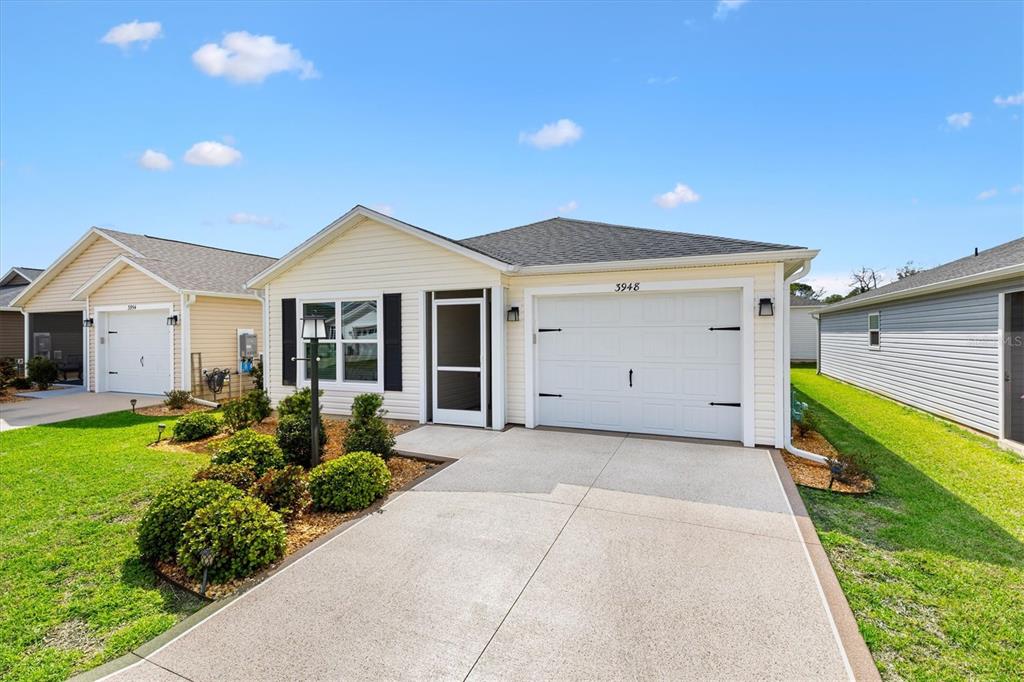 A single-story house with light yellow siding, a white garage door, and a concrete driveway — 3948 MUNFORD TERRACE, THE VILLAGES, FL