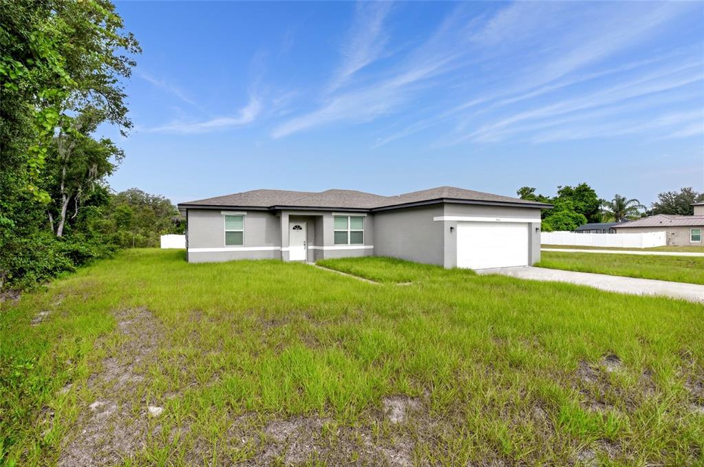 A single-story gray house with a white garage door sits on a grassy lot — 1400 SEBRING WAY, POINCIANA, FL