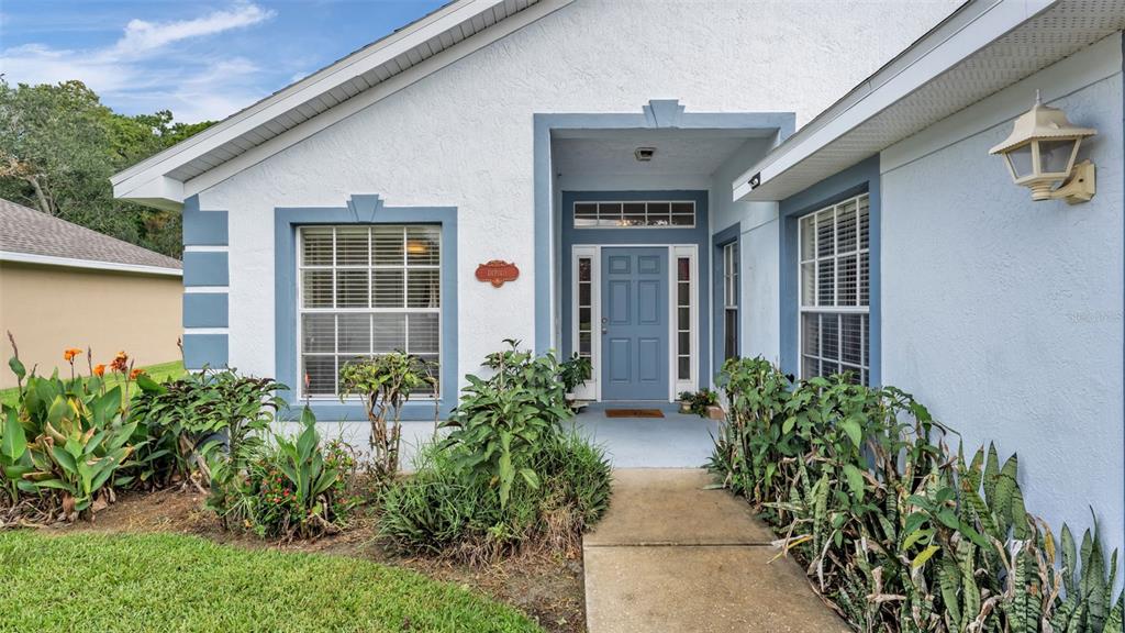 The exterior of a light blue house features a front entrance, windows, and landscaping — 1754 TURTLE ROCK DRIVE, LAKELAND, FL