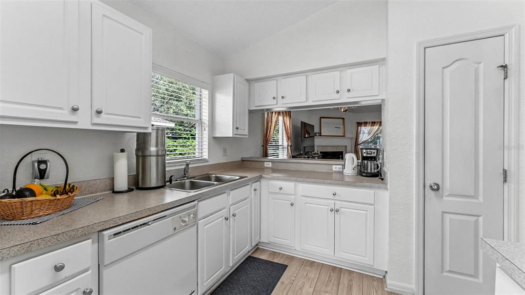 A kitchen with white cabinets, light countertops, a double sink, and a pass-through window — 1754 TURTLE ROCK DRIVE, LAKELAND, FL