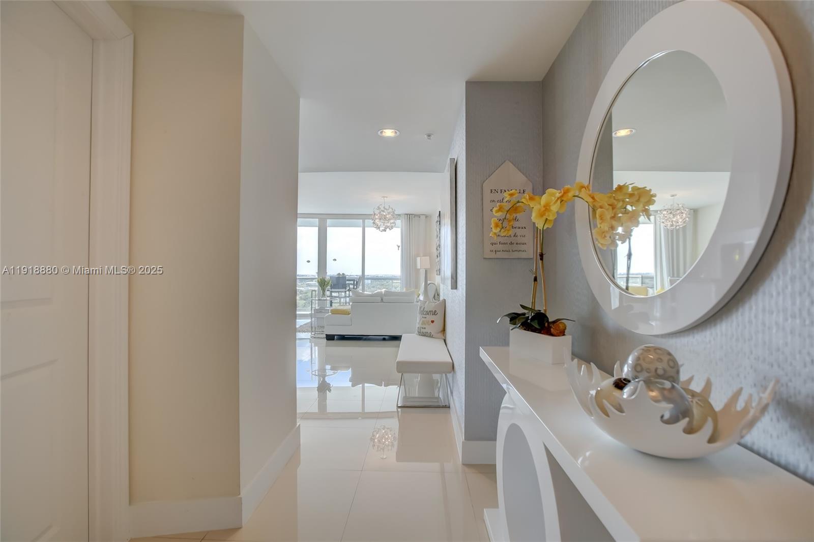 A bright hallway with white tile floors leads to a living area with floor-to-ceiling windows — 1 N Ocean Blvd # 1011, Pompano Beach FL 33062, POMPANO BEACH, FL
