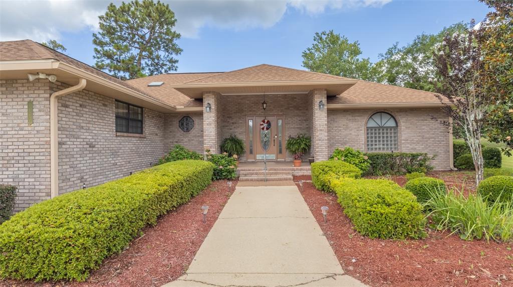 A single-story brick house with a large concrete driveway and a landscaped front yard — 4660 SE 3RD PLACE, KEYSTONE HEIGHTS, FL