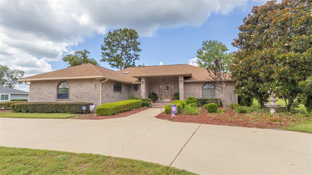 A brick house exterior features a covered entryway with a front door and landscaping — 4660 SE 3RD PLACE, KEYSTONE HEIGHTS, FL