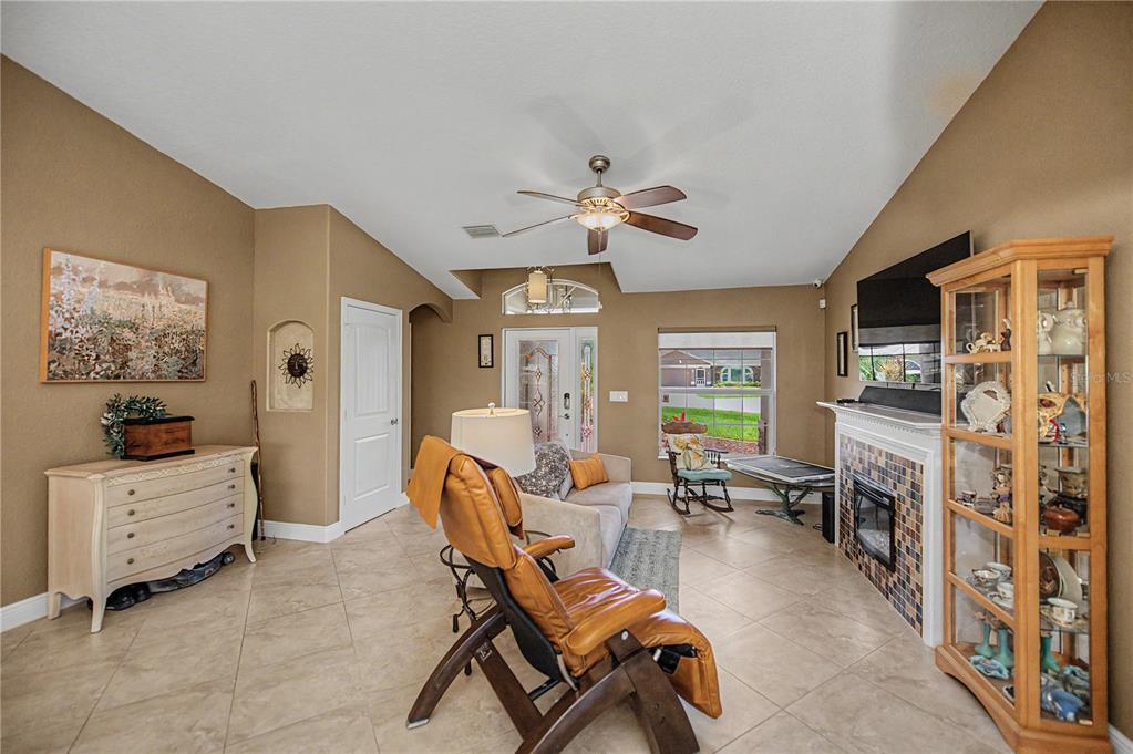 A living room features tan walls, tile flooring, a fireplace, and a ceiling fan — 419 BAHIA GRANDE AVENUE, PUNTA GORDA, FL