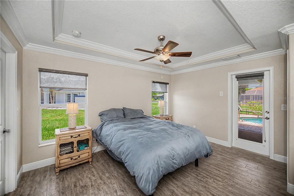A bedroom features a bed, two nightstands, a ceiling fan, and a door leading outside — 419 BAHIA GRANDE AVENUE, PUNTA GORDA, FL