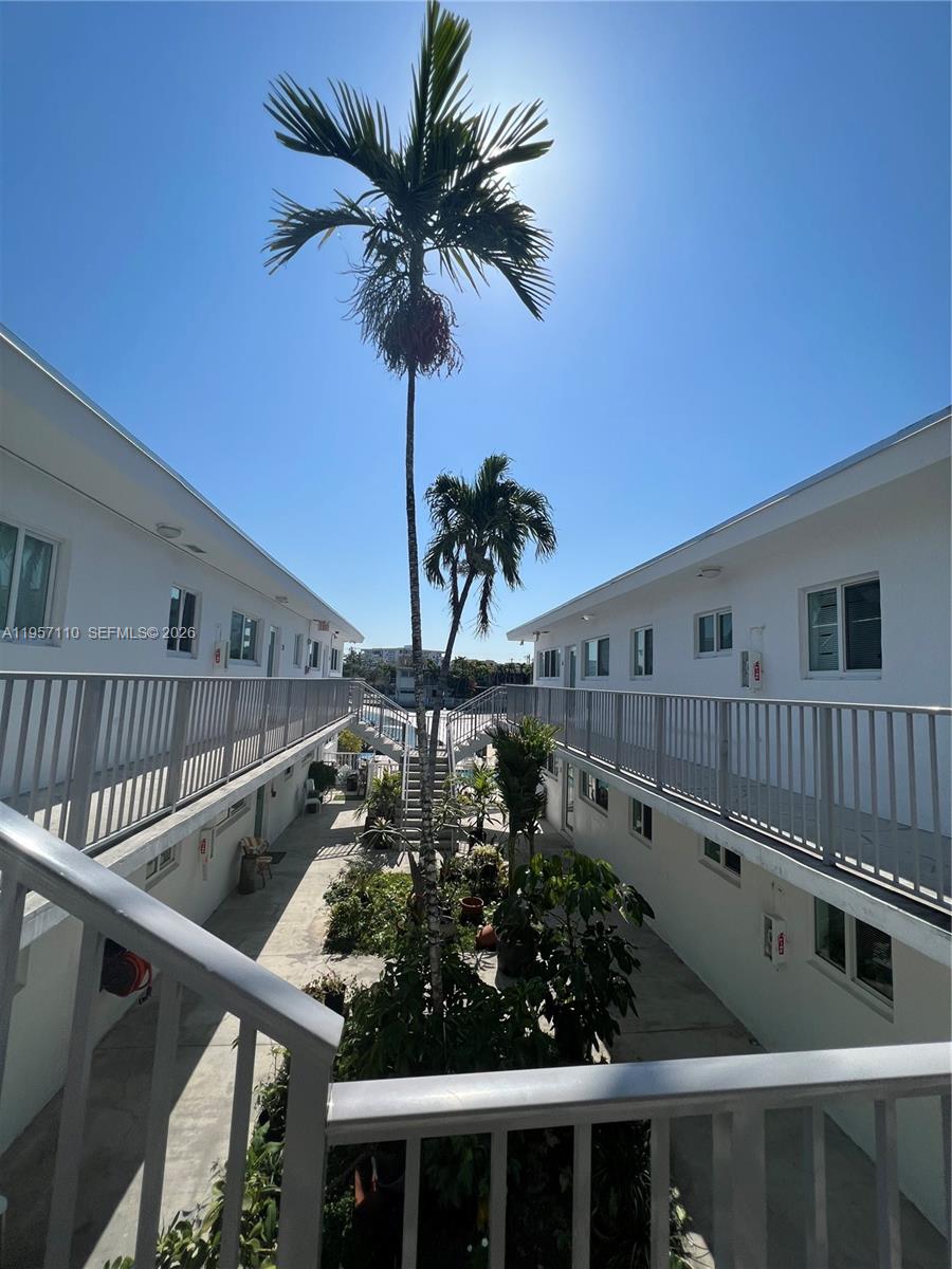 An exterior view of a two-story apartment complex courtyard with palm trees and walkways — 8035 Crespi Blvd # 1, Miami Beach FL 33141, MIAMI BEACH, FL