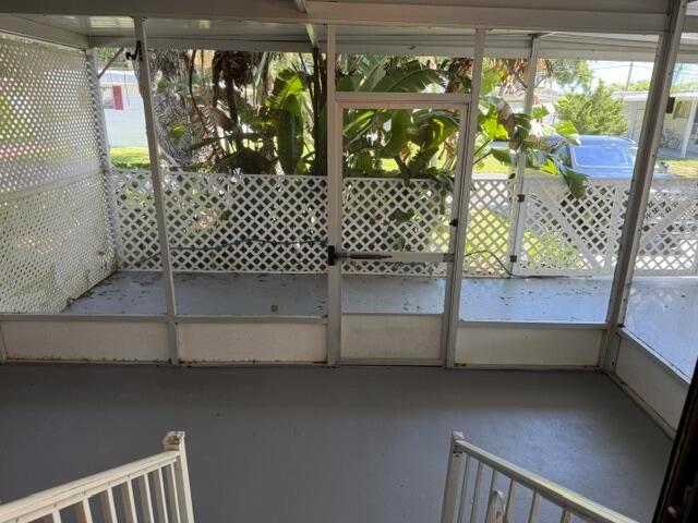 A screened-in porch with gray flooring, white lattice walls, and a central screen door — 126 Yuma Way, Fort Pierce FL 34946, FORT PIERCE, FL