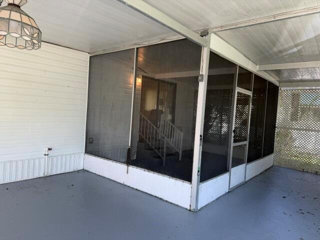 A covered patio area features a screened-in enclosure with a door and grey flooring — 126 Yuma Way, Fort Pierce FL 34946, FORT PIERCE, FL