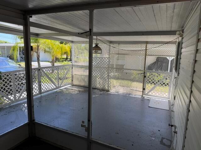 A screened-in porch with a concrete floor, white lattice walls, and a hanging light fixture — 126 Yuma Way, Fort Pierce FL 34946, FORT PIERCE, FL