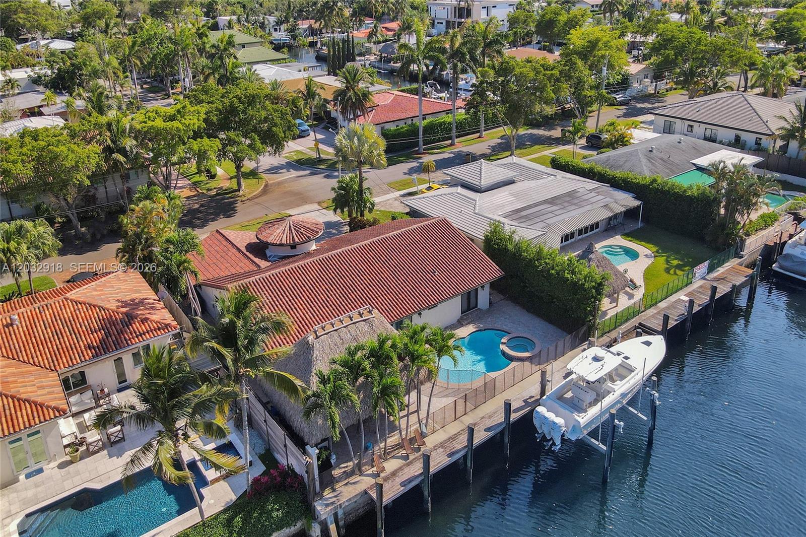 An aerial view shows waterfront homes with tiled roofs, swimming pools, and a docked boat — 2075 Ixora Rd # 0, North Miami FL 33181, NORTH MIAMI, FL