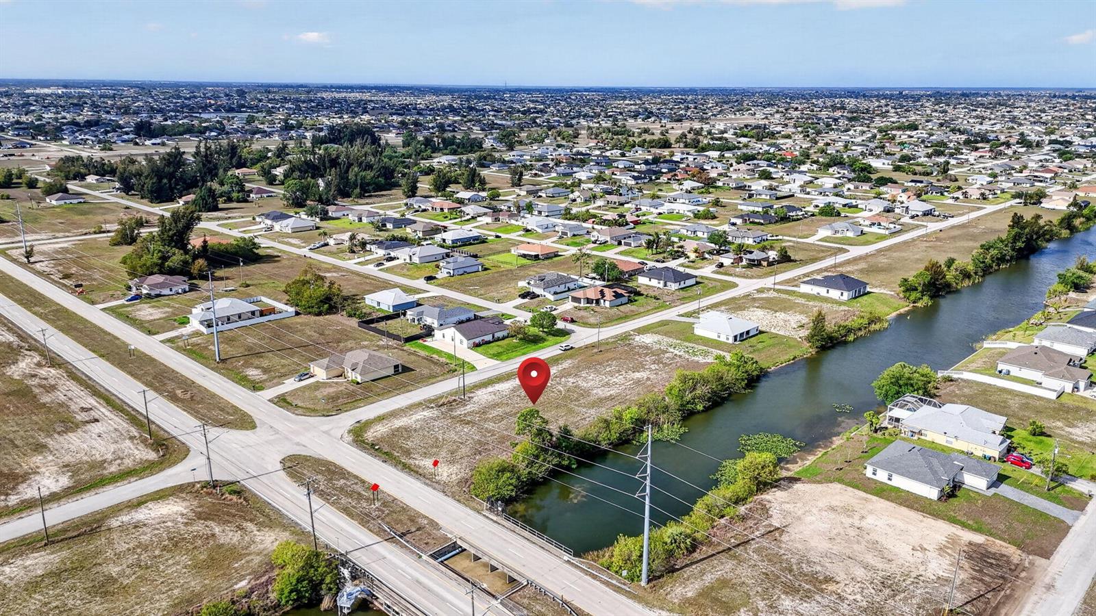 An aerial view shows a vacant corner lot next to a canal in a neighborhood — 5 NW 19th Terrace, Cape Coral FL 33993, CAPE CORAL, FL