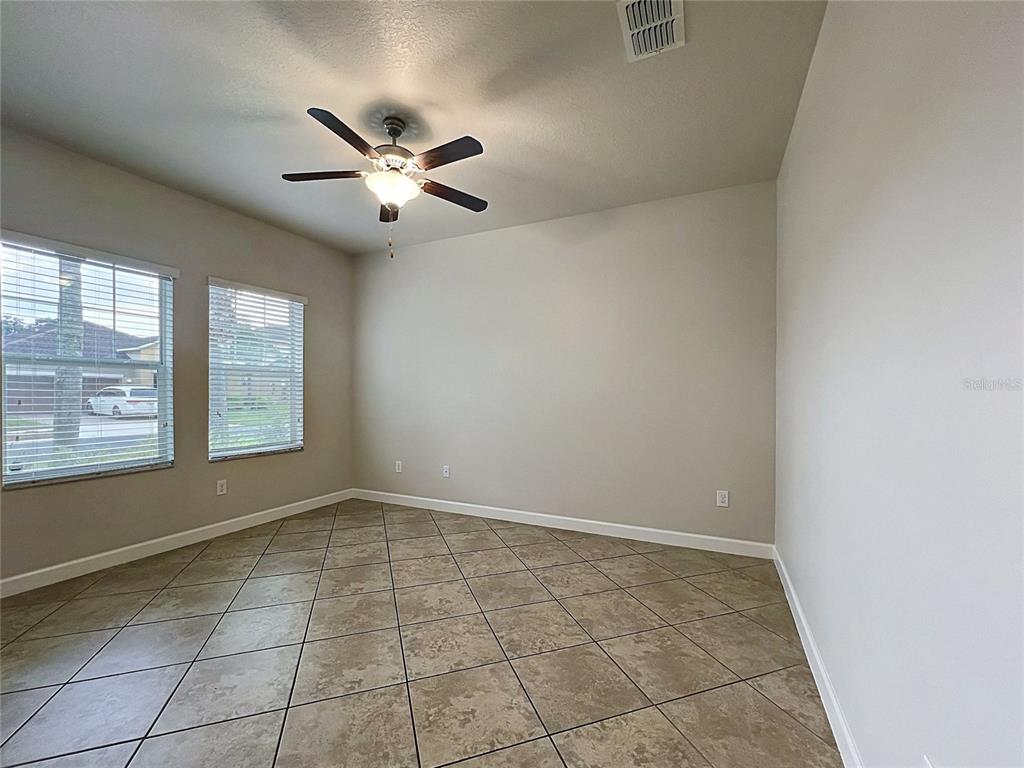 An empty room features tile flooring, a ceiling fan, and two windows with blinds — 3160 CALVANO DRIVE, LAND O LAKES, FL