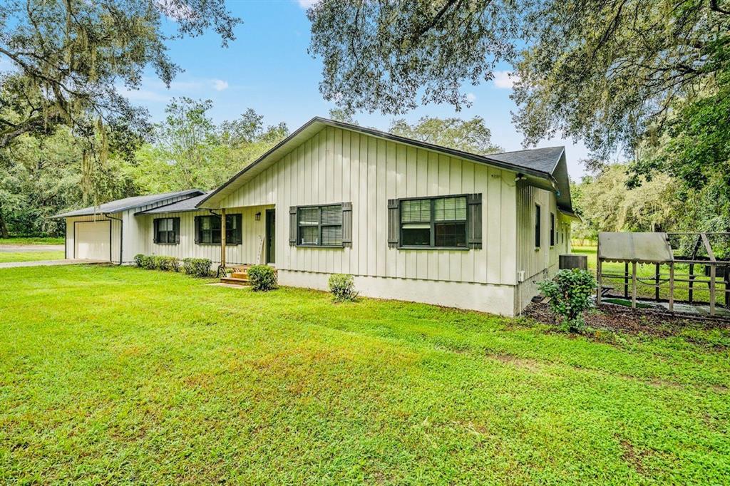 A single-story house with vertical siding, dark window shutters, and an attached garage — 10245 E TRAILS END ROAD, FLORAL CITY, FL