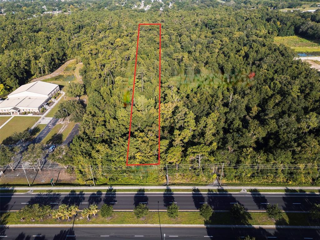 An aerial view shows a rectangular, wooded vacant lot outlined in red next to a building — 2316 ROUSE ROAD, ORLANDO, FL