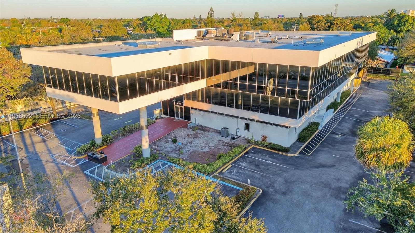 An elevated view of a two-story commercial office building with a large glass facade — 6067 Hollywood Blvd, Hollywood FL 33024, HOLLYWOOD, FL