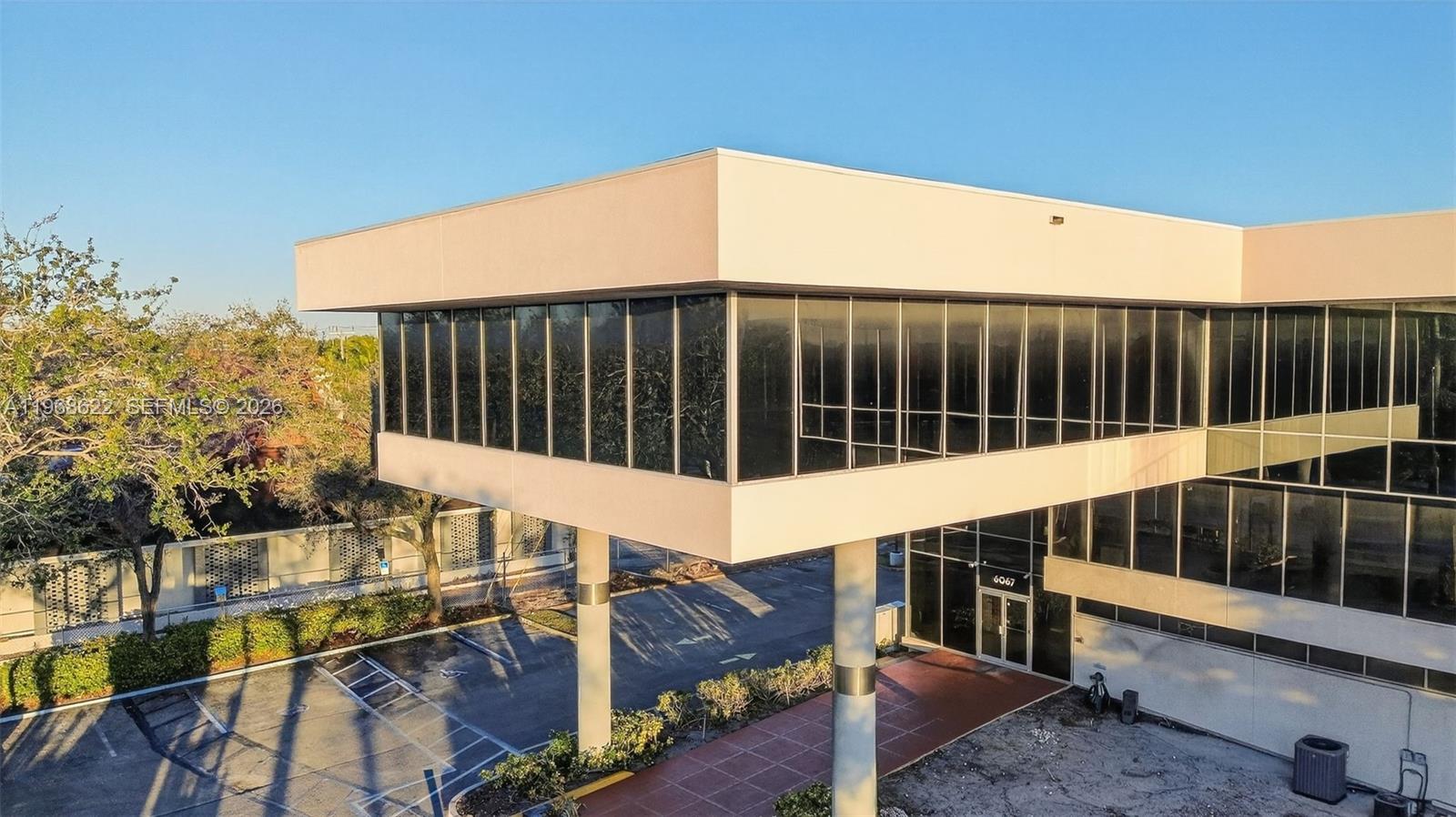 An elevated office building features a glass-walled second story supported by two large columns — 6067 Hollywood Blvd, Hollywood FL 33024, HOLLYWOOD, FL