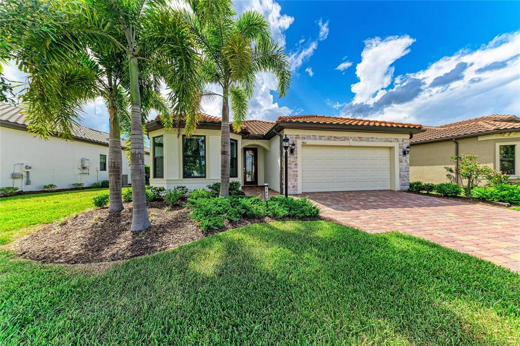 A single-story house with a paved driveway, tiled roof, and palm trees in the front yard — 7412 SUMMERLAND COVE, LAKEWOOD RANCH, FL