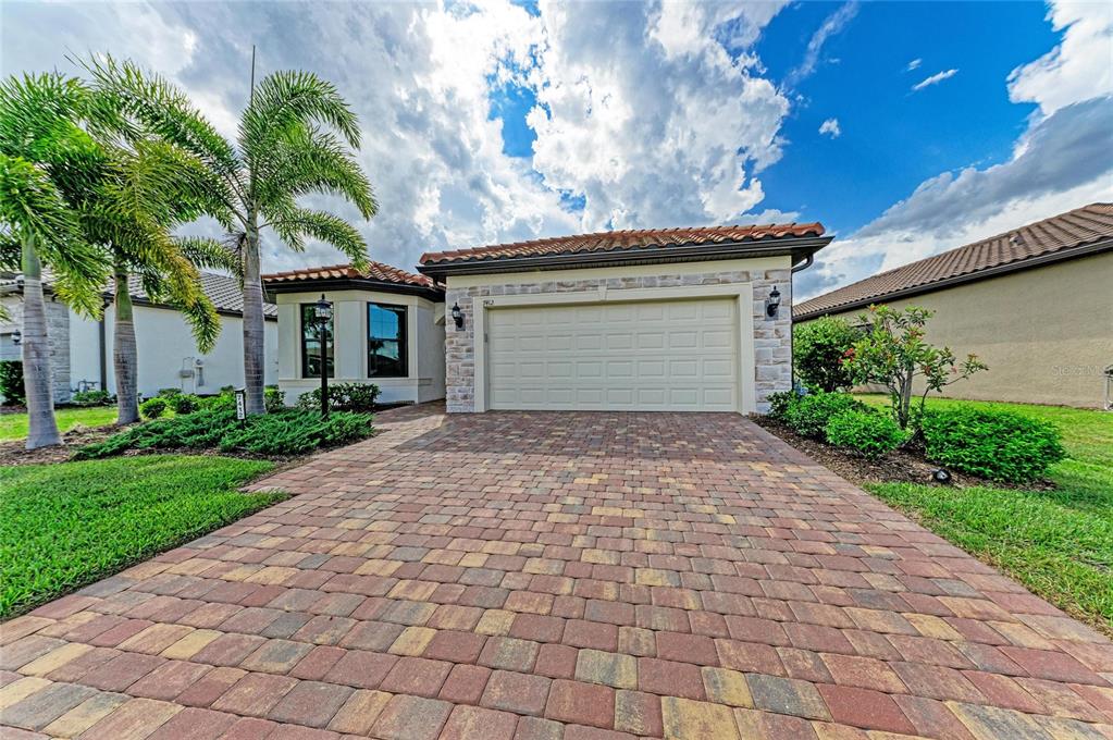 A single-story house with a stone facade, a paver driveway, and a two-car garage — 7412 SUMMERLAND COVE, LAKEWOOD RANCH, FL