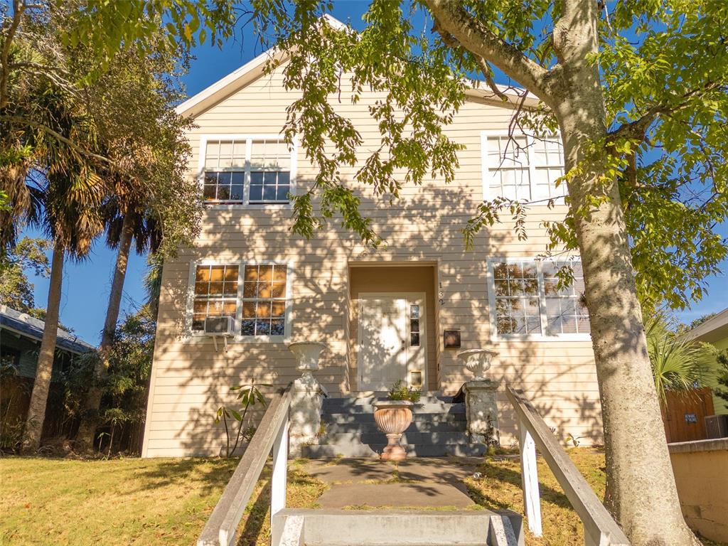 A two-story house with beige siding, a front staircase, and a white front door — 132 N PENINSULA DRIVE, DAYTONA BEACH, FL