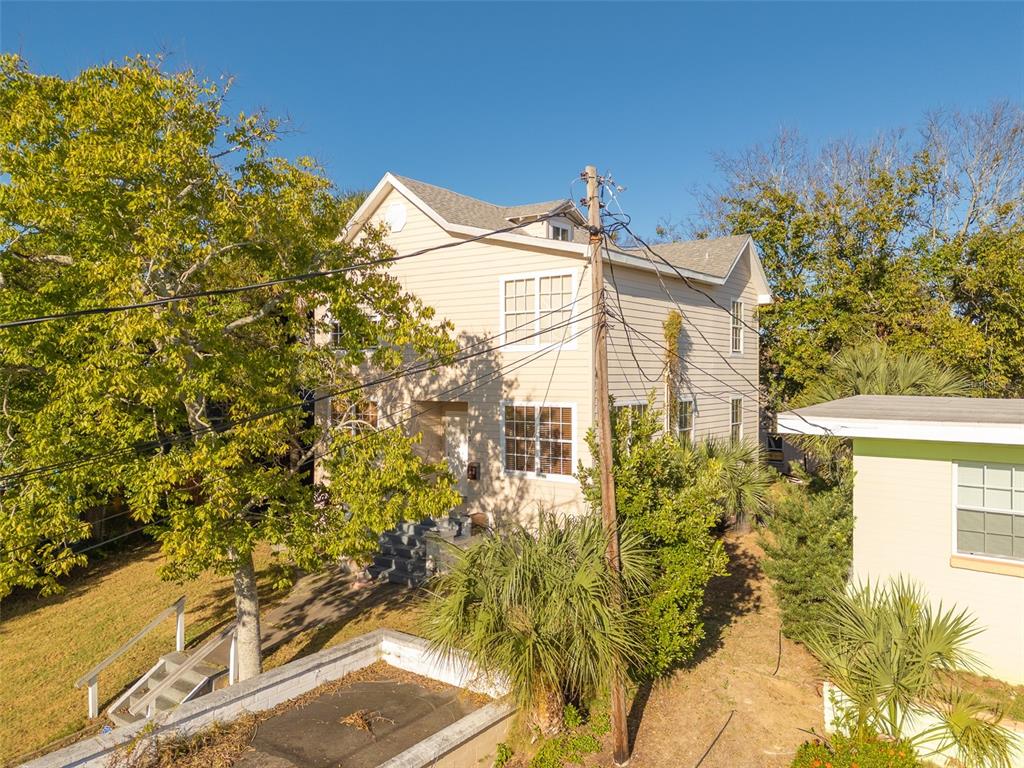 A two-story tan house with a gabled roof stands behind a utility pole and trees — 132 N PENINSULA DRIVE, DAYTONA BEACH, FL
