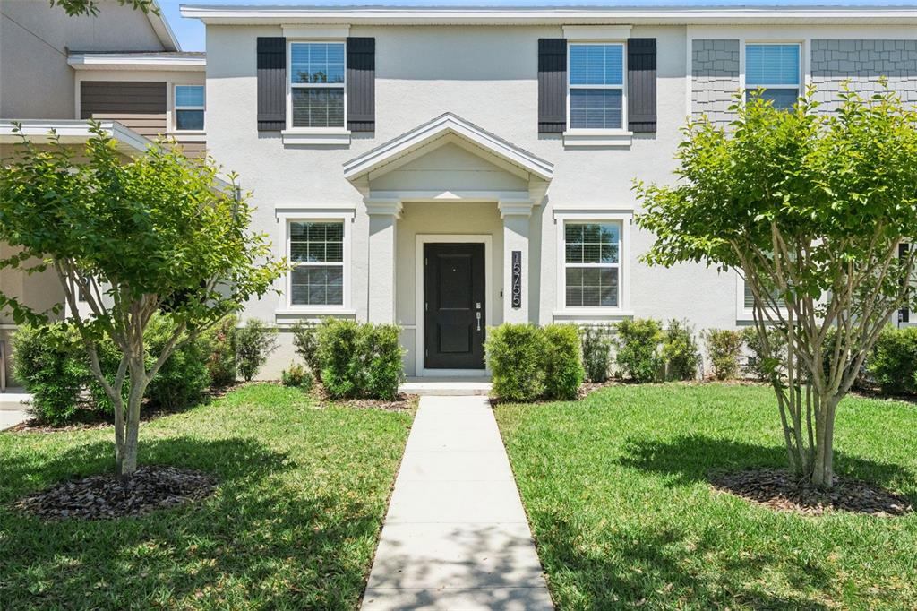 A two-story townhouse exterior features a central front door, white stucco walls, and two trees — 15755 WATER SPRING BOULEVARD, WINTER GARDEN, FL