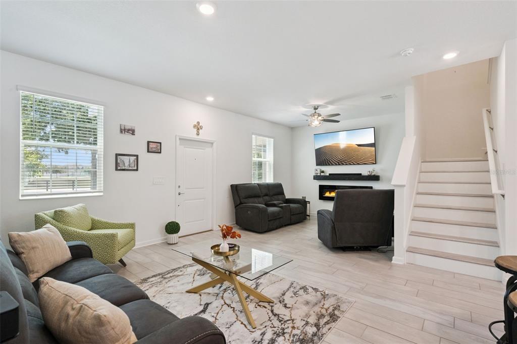 A living room features light tile floors, a fireplace with a mounted television, and stairs — 15755 WATER SPRING BOULEVARD, WINTER GARDEN, FL