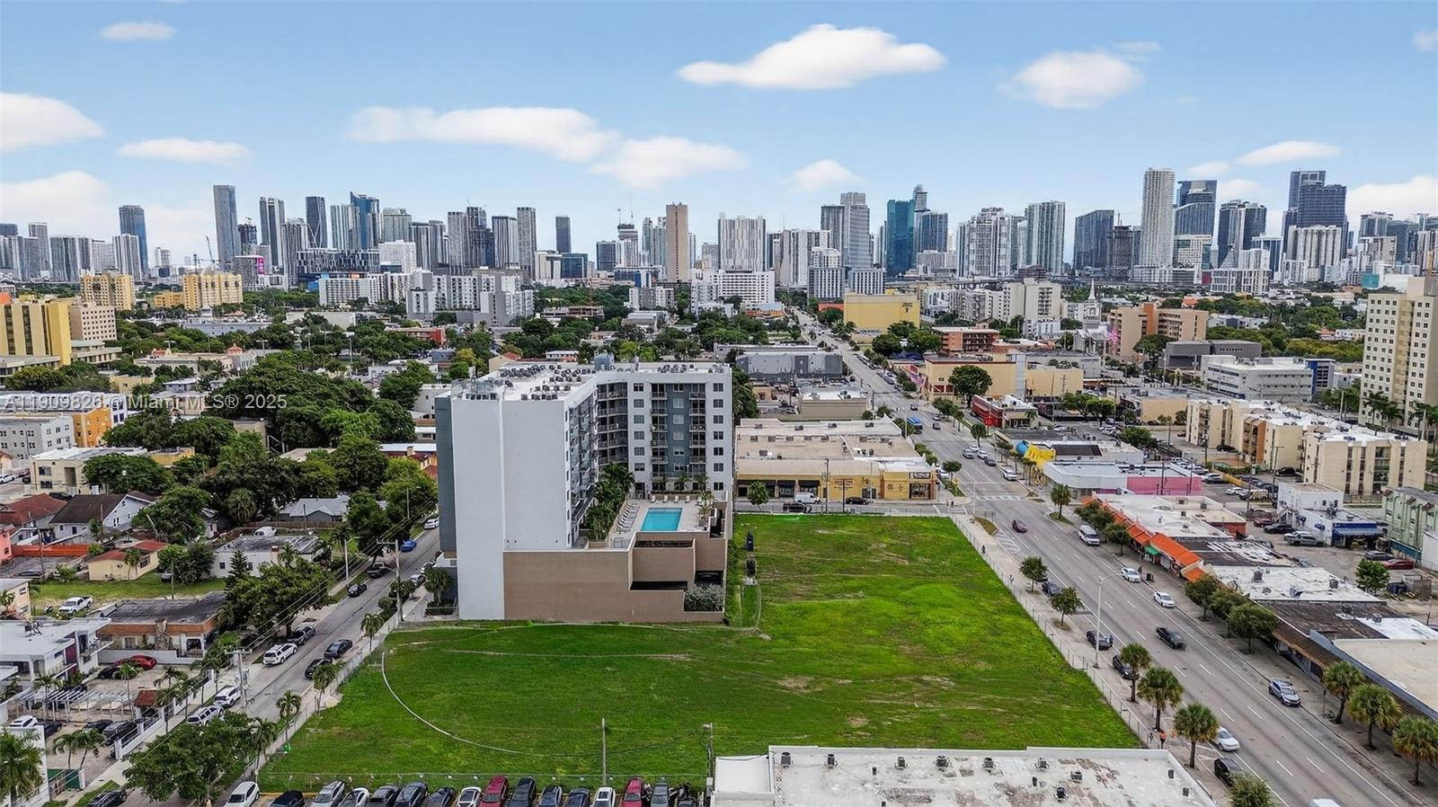 An aerial view shows a multi-story apartment building with a pool next to a vacant lot — 1110 NW 1 ST # 502, Miami FL 33128, MIAMI, FL
