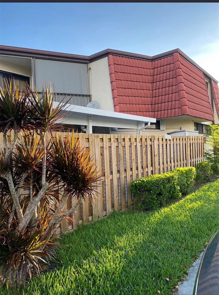 A wooden fence stands in front of a two-story building with a red tiled roof — 3940 Victoria Dr, West Palm Beach FL 33406, WEST PALM BEACH, FL