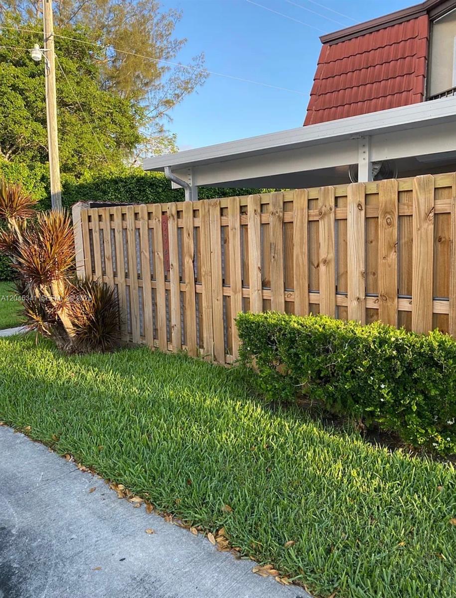 A wooden privacy fence stands in front of a house with a red roof — 3940 Victoria Dr, West Palm Beach FL 33406, WEST PALM BEACH, FL