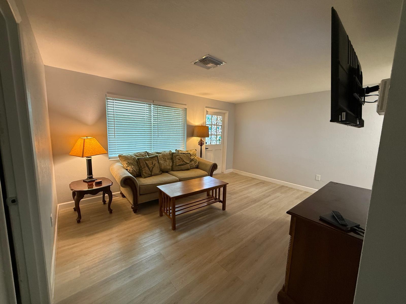 A living room features light wood flooring, a sofa, a coffee table, and a wall-mounted television — 9015 Twig Road, Lake Worth FL 33467, LAKE WORTH, FL