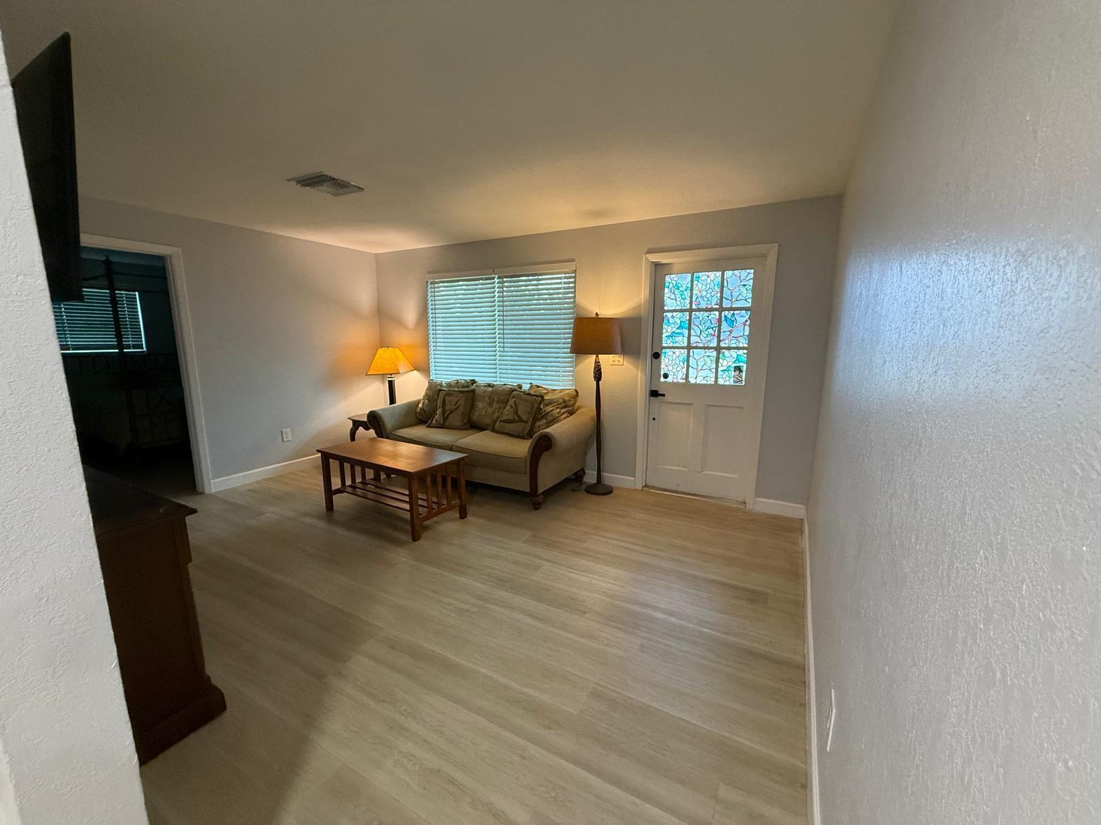A living room features light wood-look flooring, a beige sofa, a coffee table, and a door — 9015 Twig Road, Lake Worth FL 33467, LAKE WORTH, FL