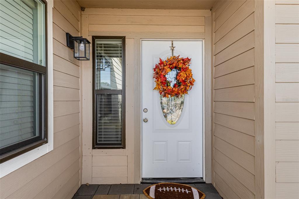 A tan house exterior features a white front door with an autumn wreath and doormat — 5225 IMPERIAL LAKES BOULEVARD UNIT 57, MULBERRY, FL