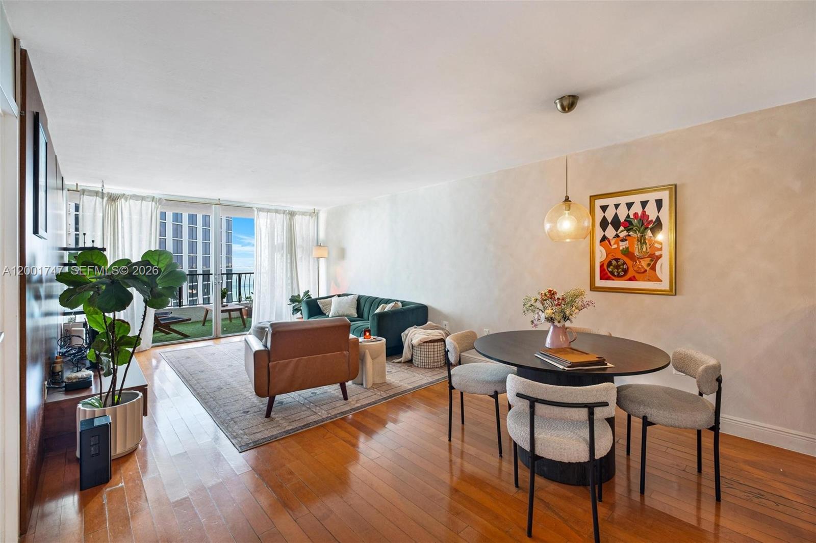 This living and dining area features hardwood floors, a balcony, and modern furniture — 555 NE 15th St # 26F, Miami FL 33132, MIAMI, FL