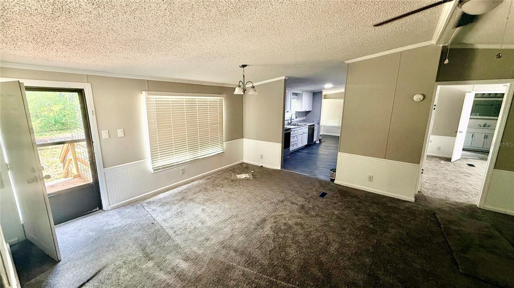 A living room with gray carpet, white wainscoting, and an open view into the kitchen — 7350 SE 78TH PLACE, TRENTON, FL