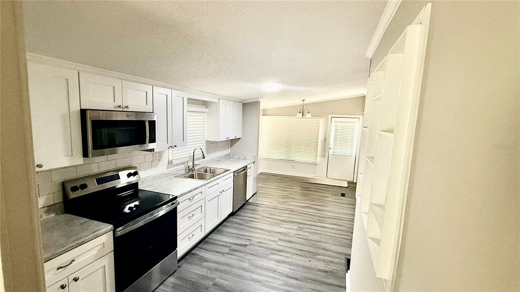 A kitchen with white cabinets, stainless steel appliances, and gray wood-look flooring — 7350 SE 78TH PLACE, TRENTON, FL