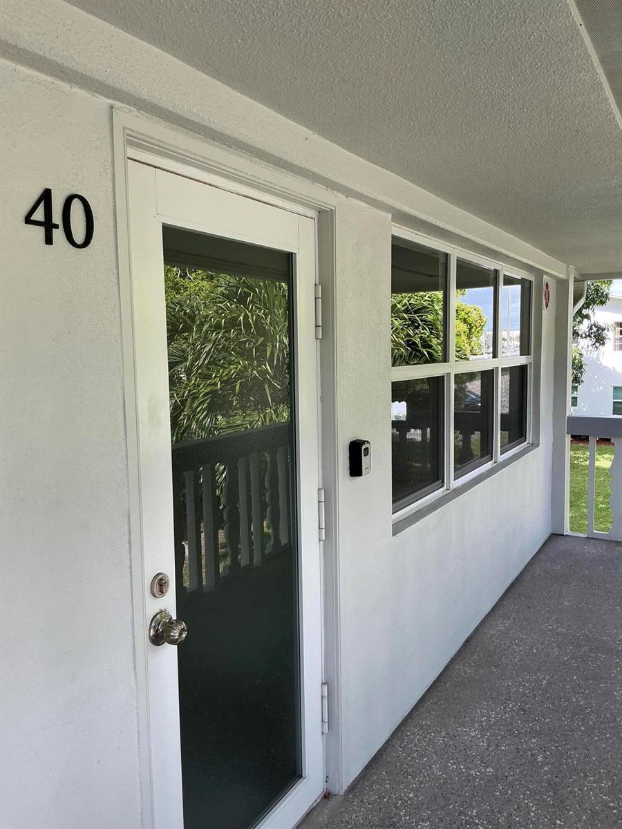 A white exterior door numbered 40 with a window and a nearby window on a walkway — 40 Ventnor Drive, Deerfield Beach FL 33442, DEERFIELD BEACH, FL