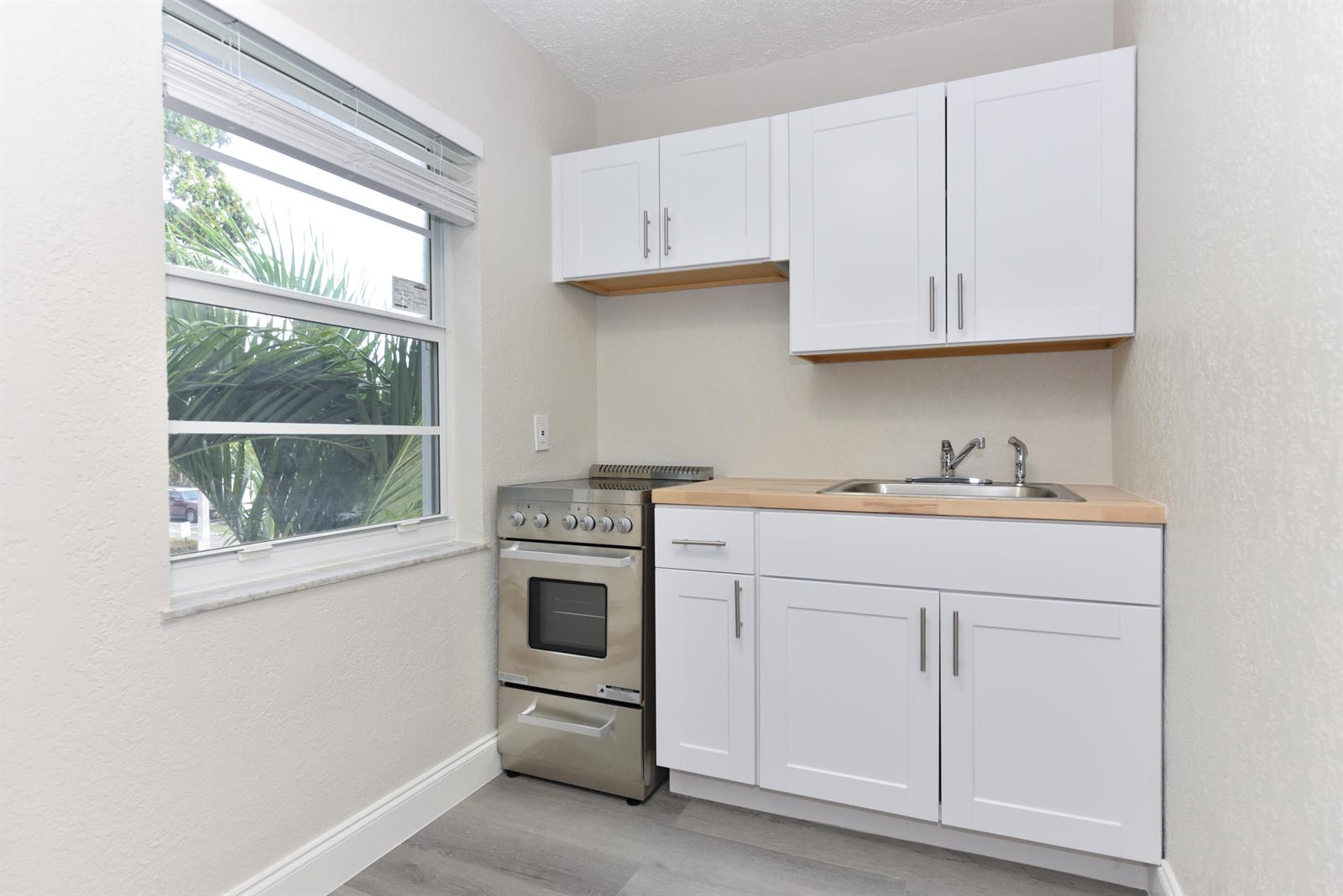 A small kitchen features white cabinets, a stainless steel stove, and a light wood countertop — 605 N Federal Highway # 7, FL 33460, FL