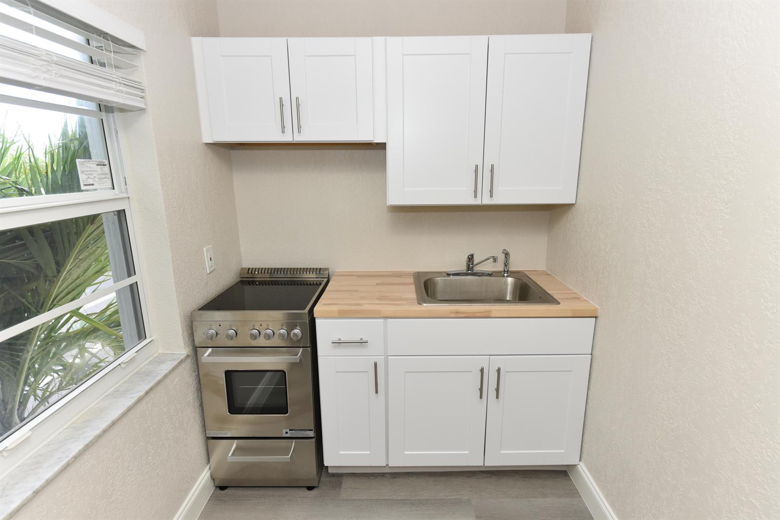 A small kitchen area features white cabinets, a stainless steel stove, and a wooden countertop — 605 N Federal Highway # 7, FL 33460, FL