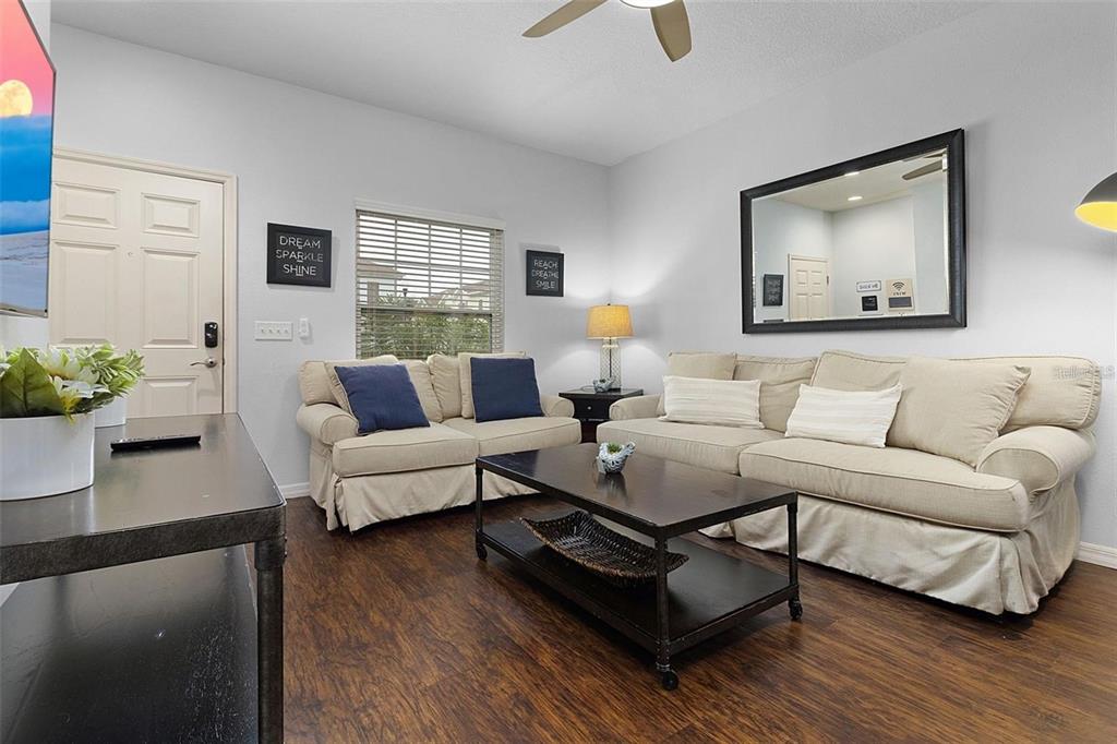 A living room features two beige sofas, a dark coffee table, and a large wall mirror — 3203 OYSTER LANE, KISSIMMEE, FL