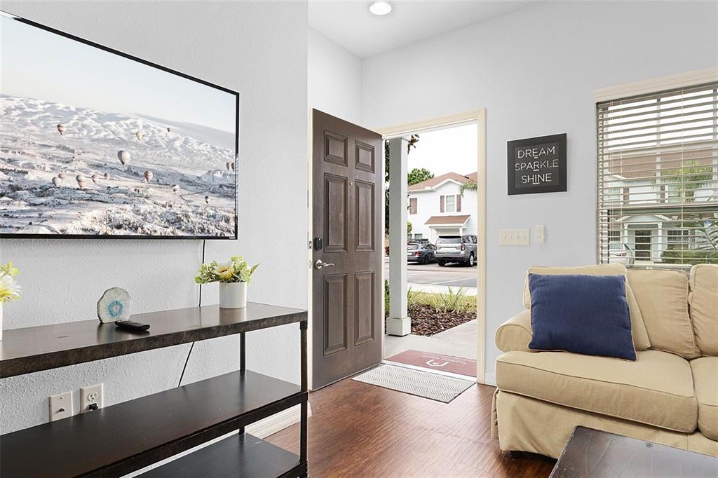 A living room features a television, a console table, a sofa, and an open front door — 3203 OYSTER LANE, KISSIMMEE, FL