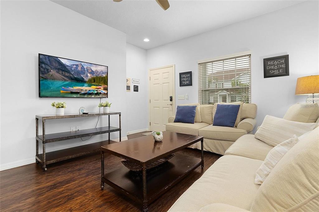 A living room features a television on a metal stand, a coffee table, and sofas — 3203 OYSTER LANE, KISSIMMEE, FL