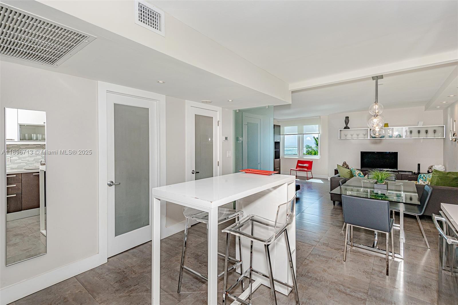 A modern open-concept living area features a kitchen island, dining table, and tile flooring — 2301 Collins Ave # 723, Miami Beach FL 33139, MIAMI BEACH, FL