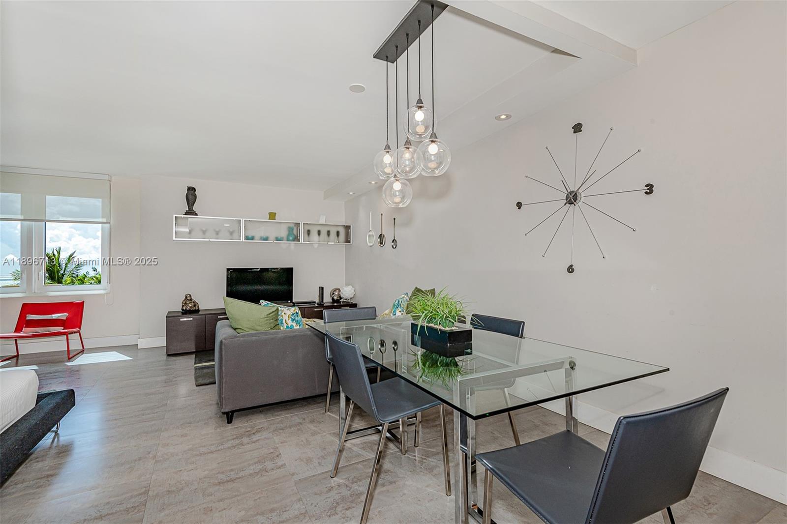 A dining area with a glass table and modern pendant lights sits beside a living room — 2301 Collins Ave # 723, Miami Beach FL 33139, MIAMI BEACH, FL