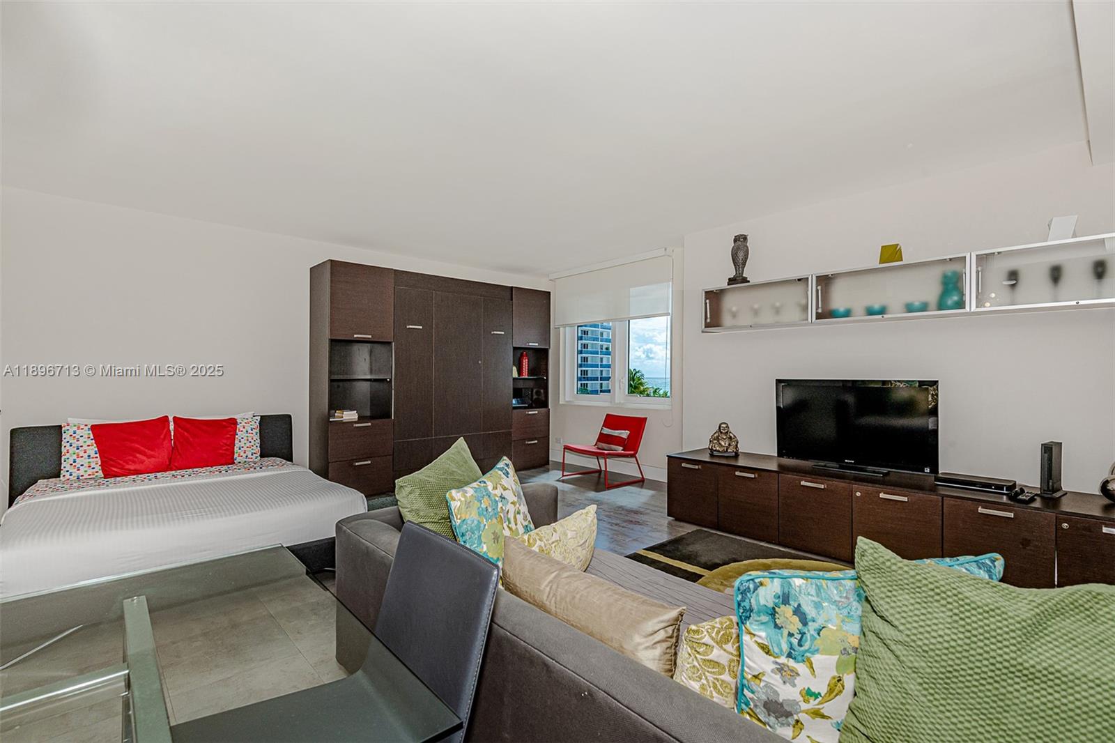 A studio apartment features a bed, a sofa, a media console, and a window view — 2301 Collins Ave # 723, Miami Beach FL 33139, MIAMI BEACH, FL