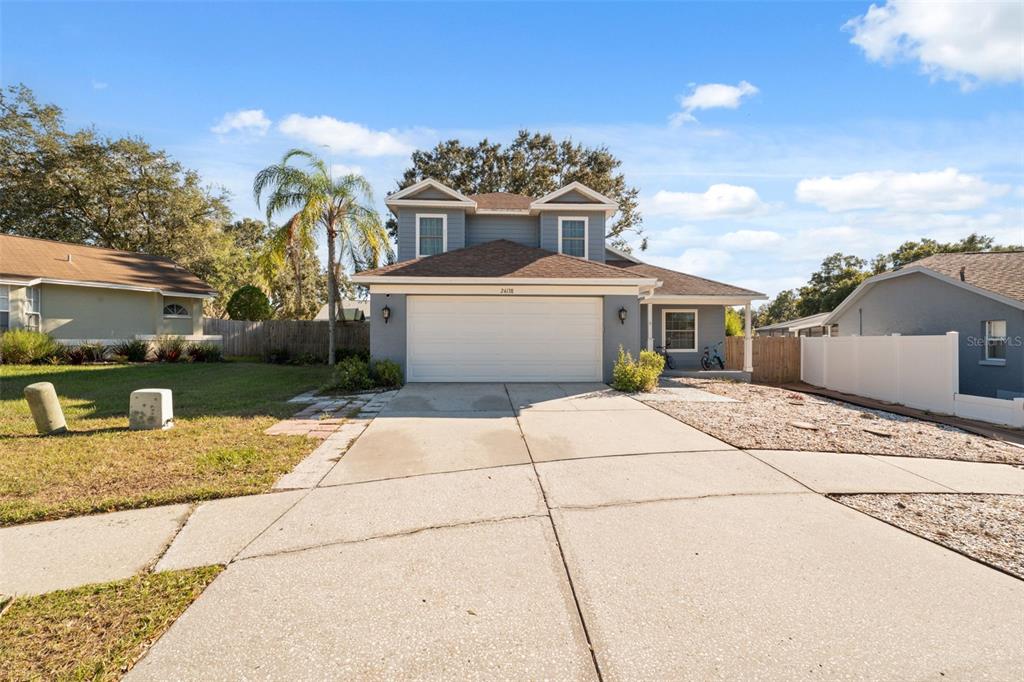A two-story house with a two-car garage, gray siding, and a concrete driveway — 24138 TWIN COURT, LAND O LAKES, FL